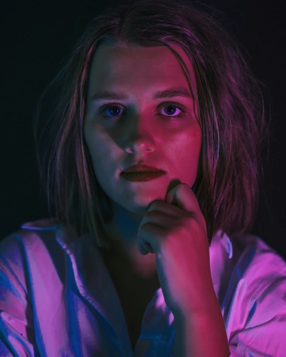 a girl looking to her left while sitting in a dark room