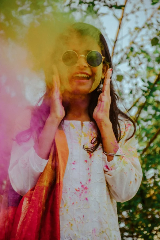 a woman with her hands on the head and sunglasses, smiling