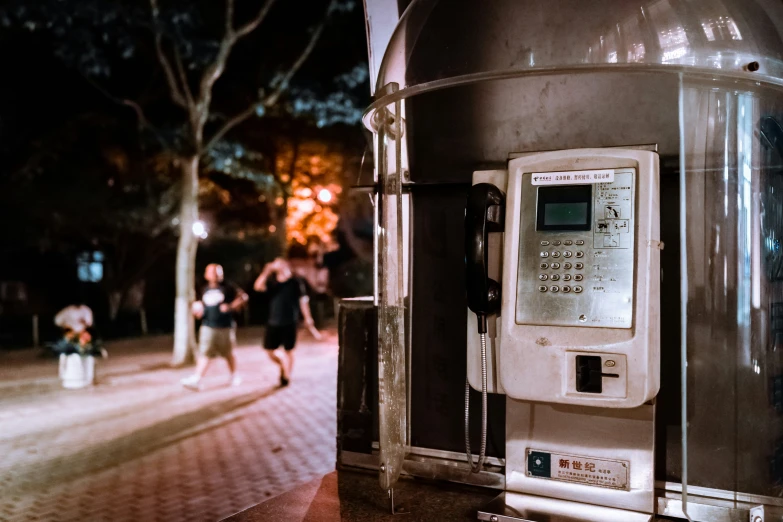 a old style phone with people walking past