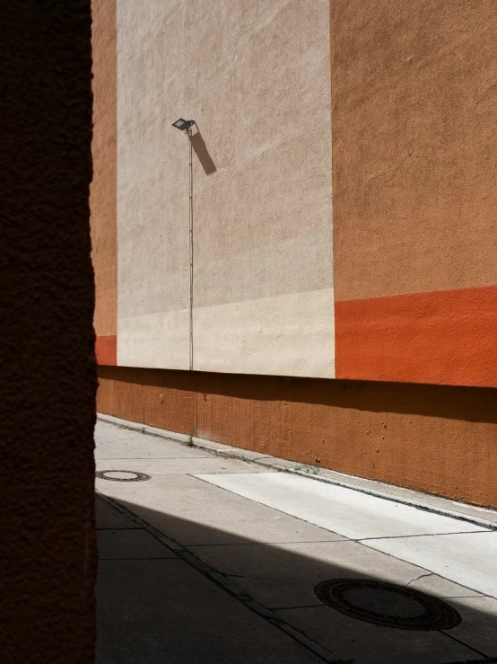 a sidewalk in front of an orange wall