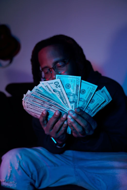 man hiding his face behind stacks of money