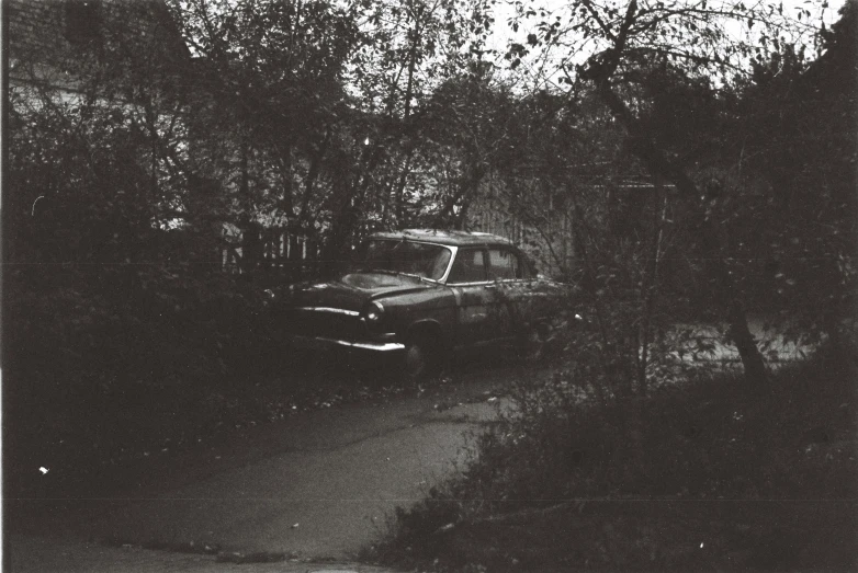 old car parked in the street by a house