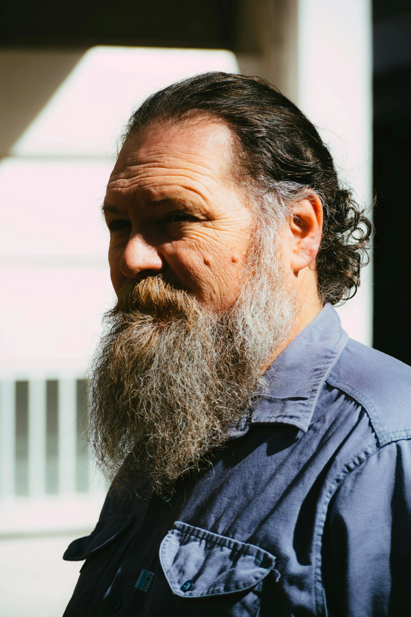 a bearded man with a greying beard is standing outside