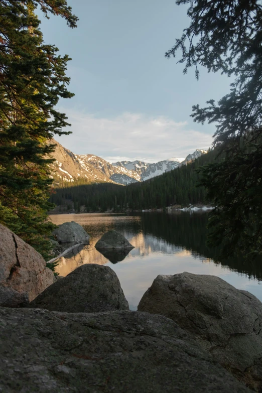 some rocks are in the water and mountains near them