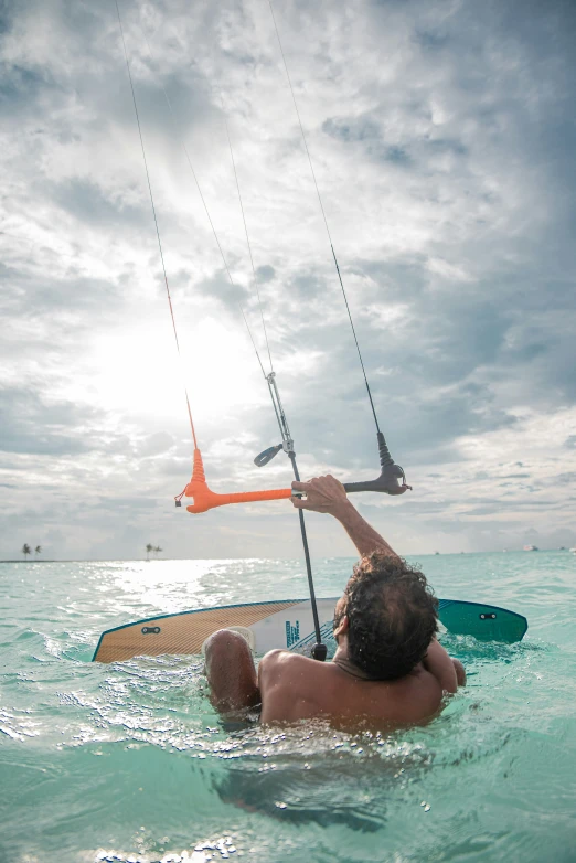 a man is floating on a surfboard in the ocean and holding the handle to a sail boat