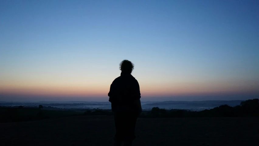 a man standing at dusk while looking at the sky