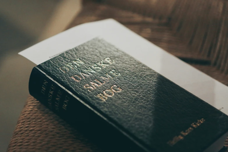 an old black bible that is next to some books