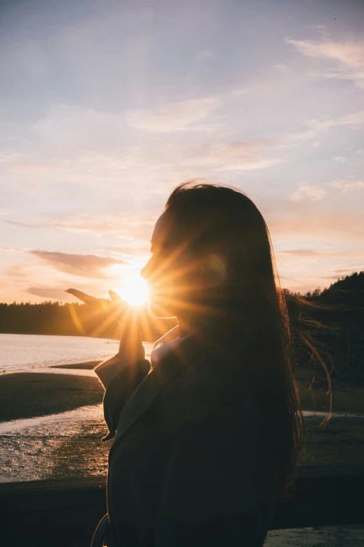 a woman is silhouetted against the sun at twilight