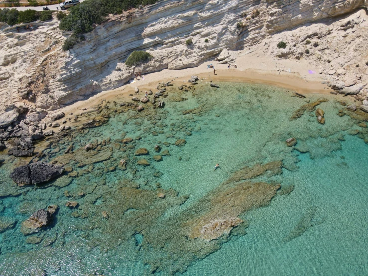 some people standing on the beach with the blue water