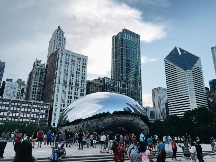 people walking through the city in front of a giant beanle bean in chicago