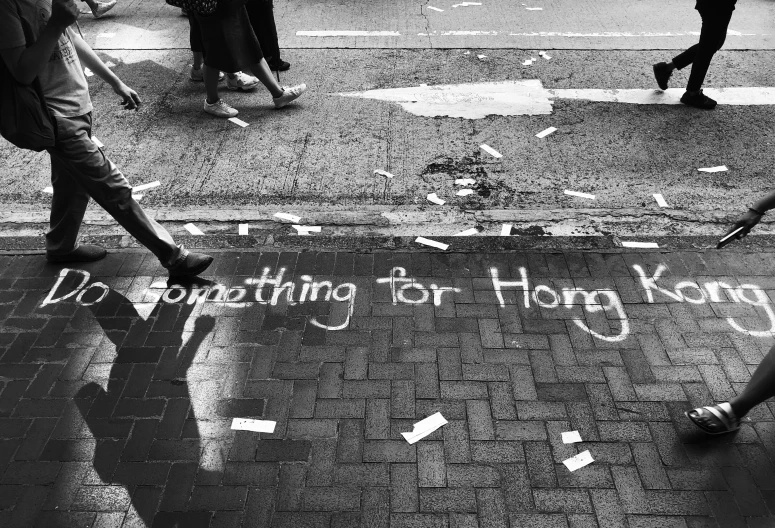 people walking down a street near a curb with message written on it