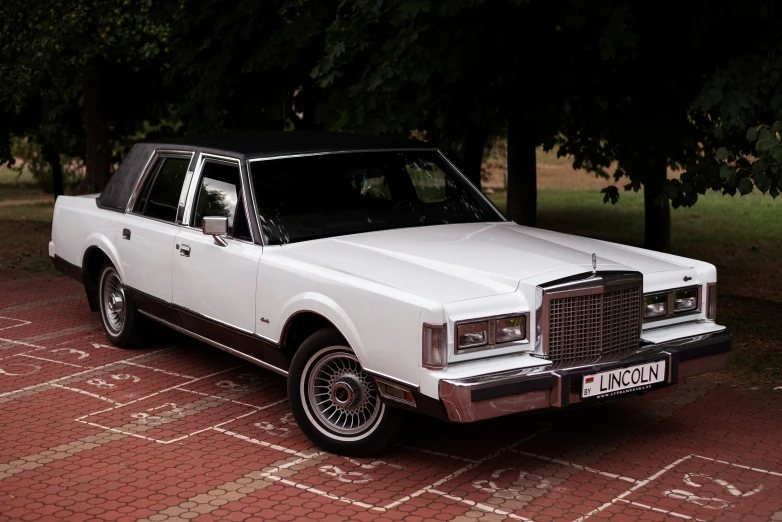 a white car sitting in front of some trees