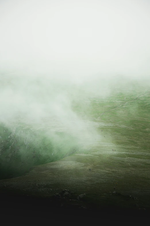 a hill covered with fog under a white sky