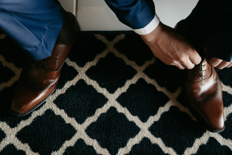 a man tying his shoelaces on top of a black and white rug