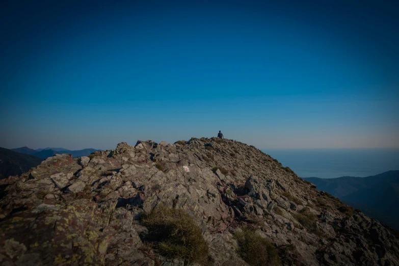 two people standing on top of a rocky hill