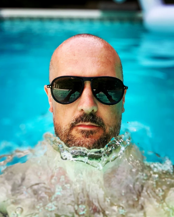 a man with sunglasses swimming in a pool