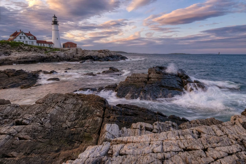 a lighthouse on the rocks with waves coming in