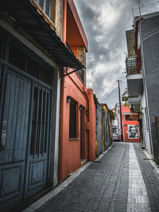 an alley lined with old city buildings under cloudy skies