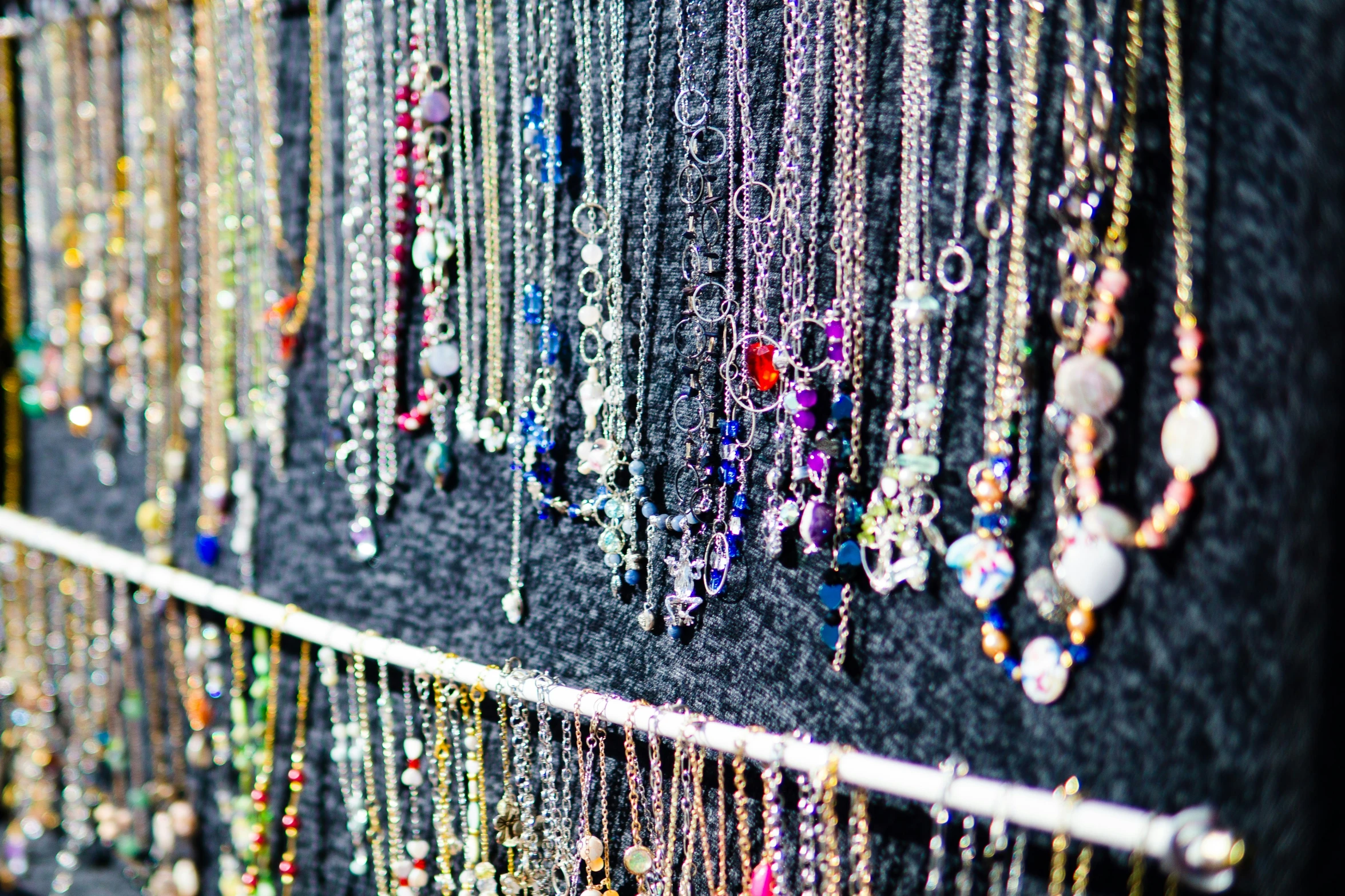 many necklaces are hanging on a wall and displayed