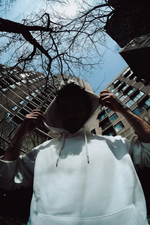 a man with a hood on in front of a tall building