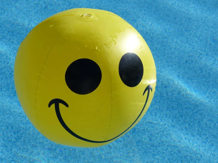 an odd smiley face balloon floats in the pool