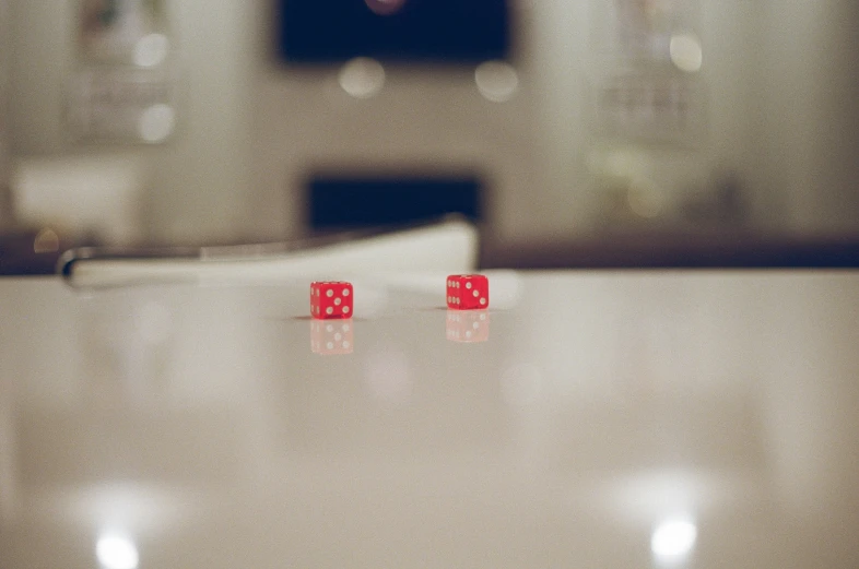 two red dices sitting on top of a white table