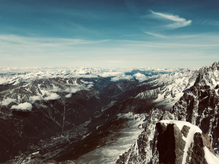 an aerial view of mountains in winter with clouds