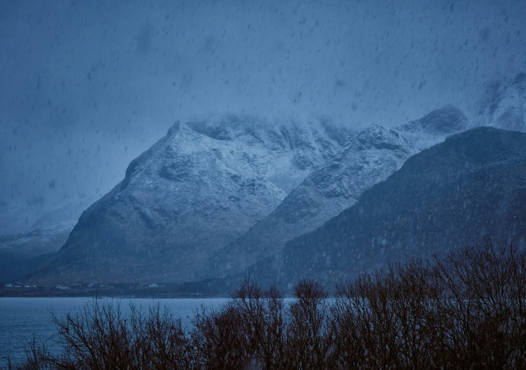 snow is falling over the mountains and water