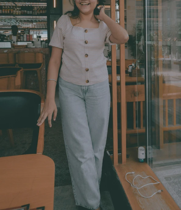 a woman walking out a cafe talking on her phone