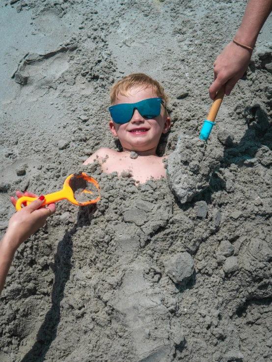 boy buried in the sand at the beach