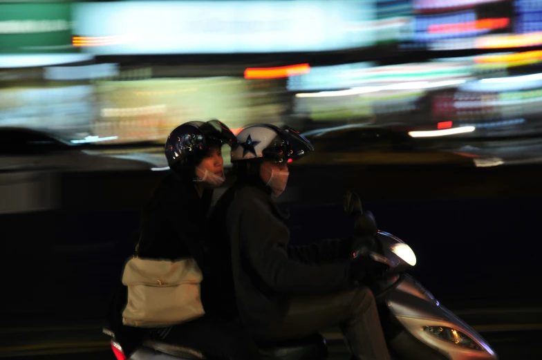 two people in helmets on a motor scooter