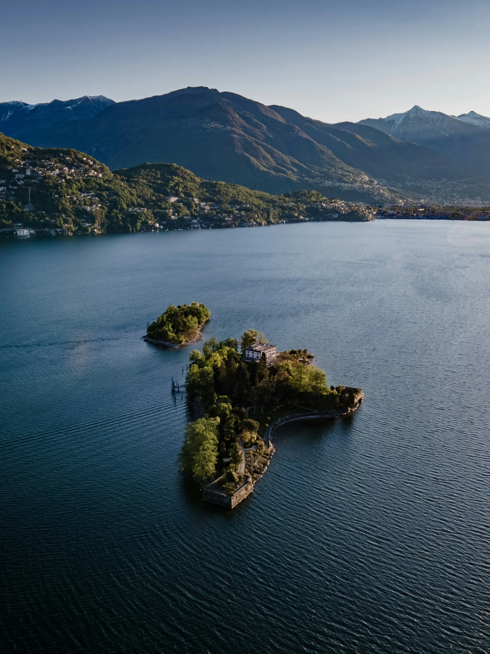 two small islands surrounded by mountains sit in the middle of a lake