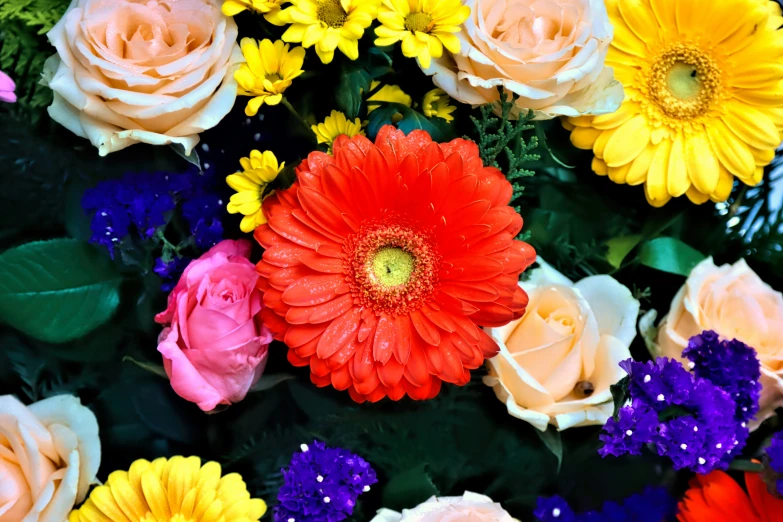 multicolored flowers arranged with green leaves and pink yellow red purple blue