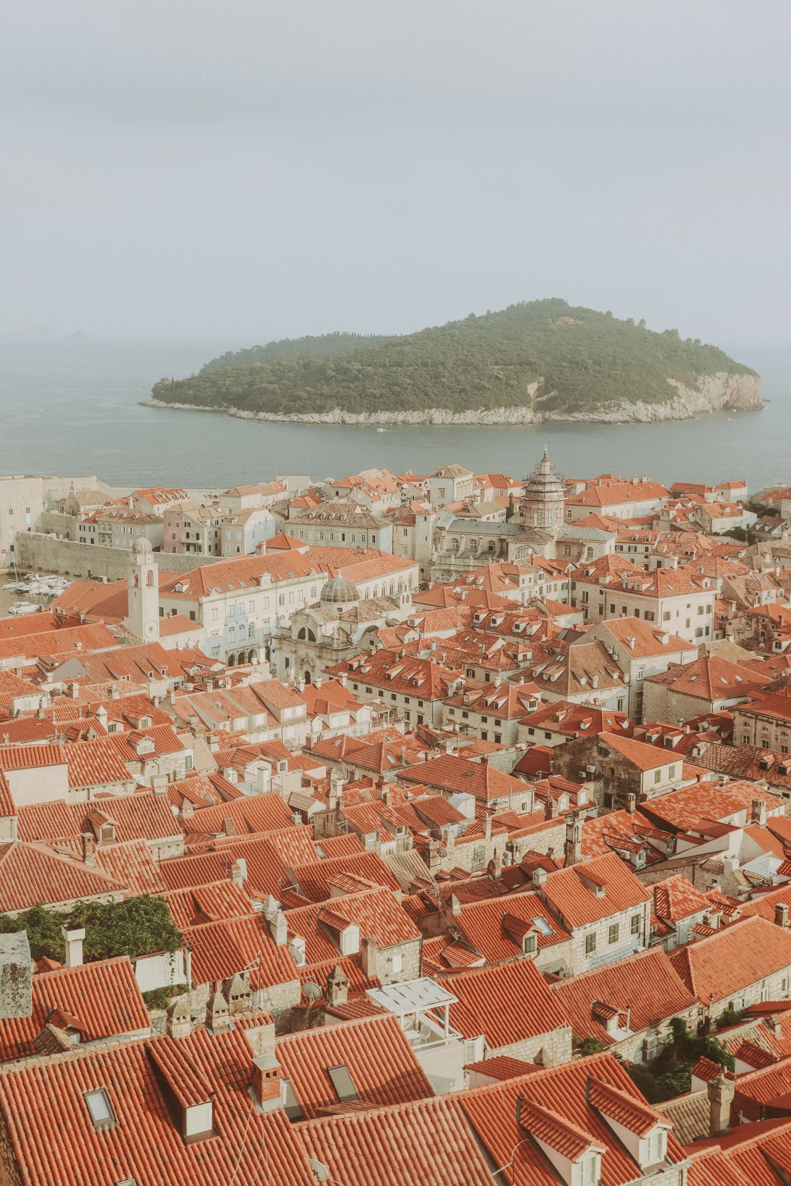 a city with orange roofs and a large island in the background