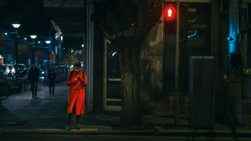 a woman in red on a city street at night