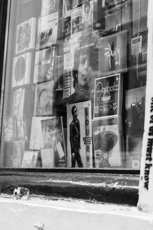 a man looking at a store window with lots of posters