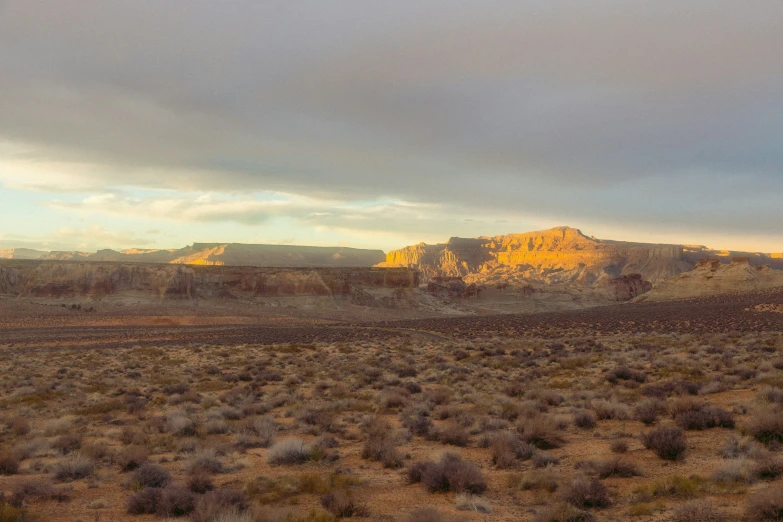 an arid landscape with a big rock out in the distance