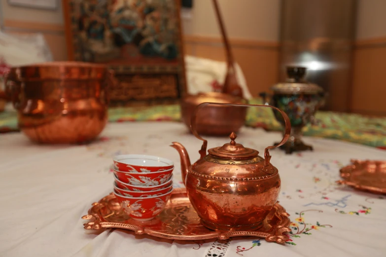 copper tea pot sitting on top of a tray next to cups