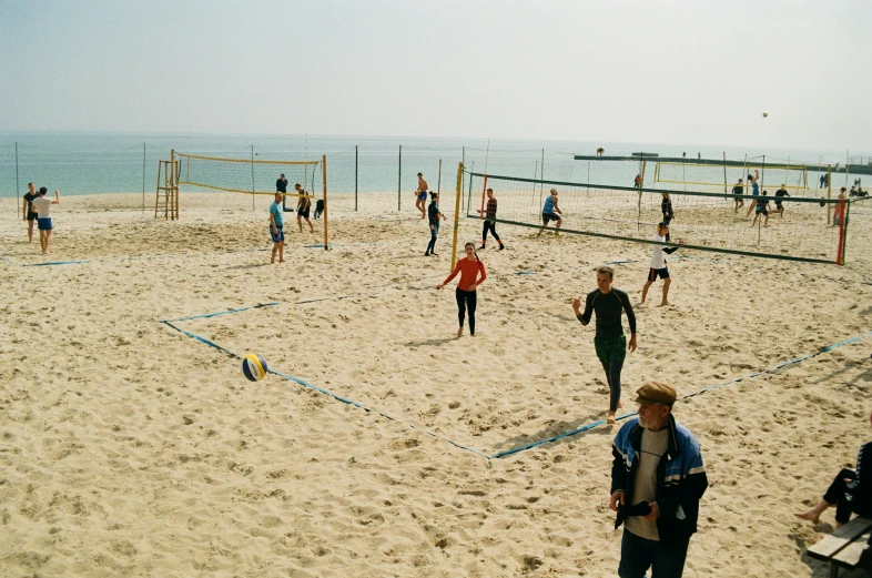 a large group of people standing on top of a sandy beach