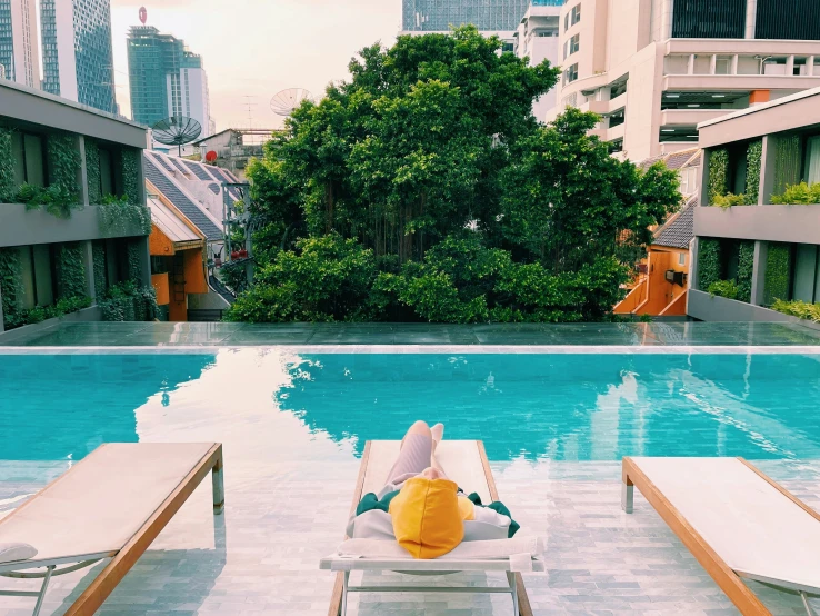 someone is relaxing on their chaise lounge next to the pool