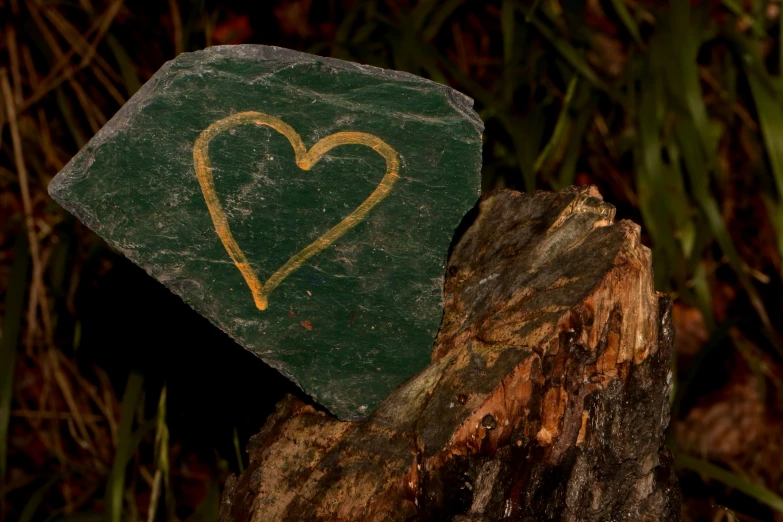 a piece of wood with a heart and golden ink in it