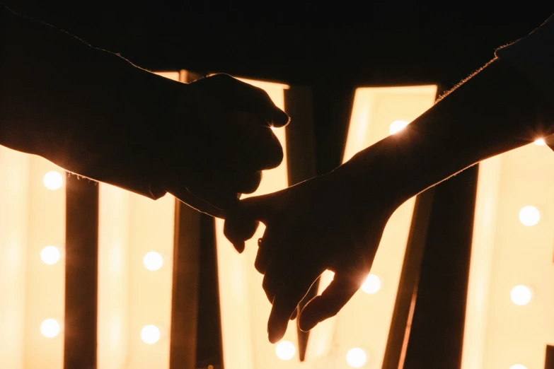 two hands are touching each other with lights behind them