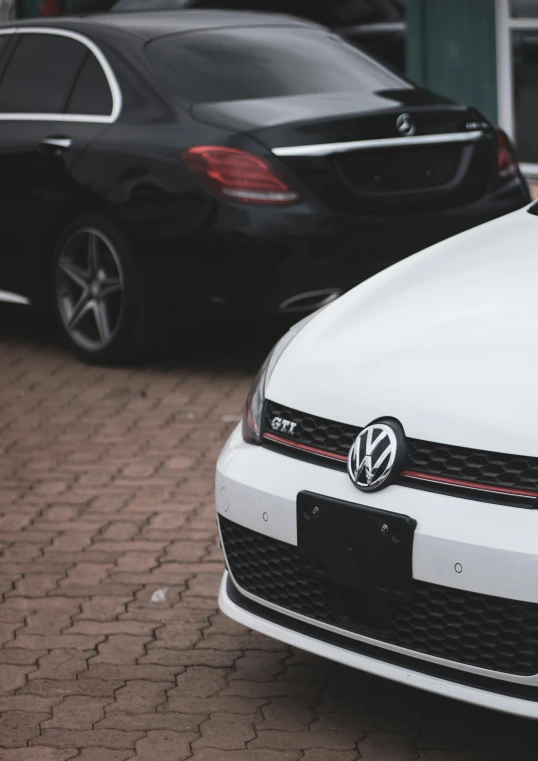 white vw golf car parked beside black mercedes c class