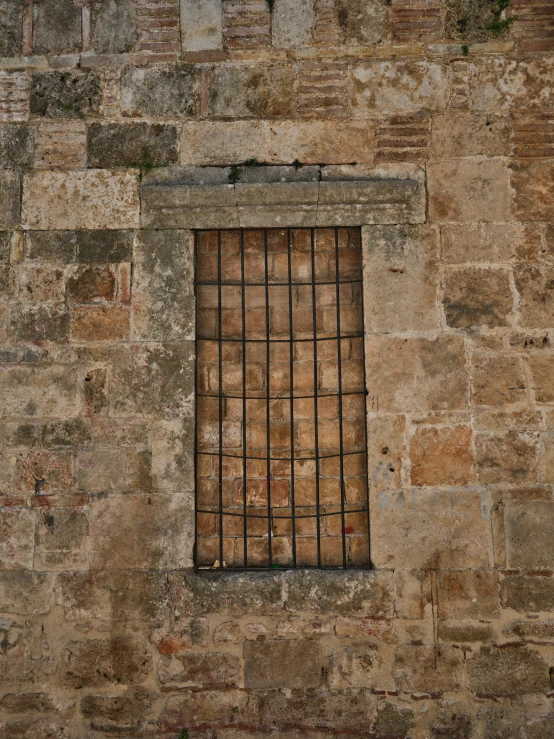 a window in a stone wall with bars on it