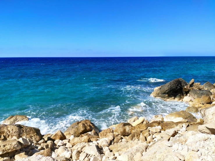 a rocky beach with some blue water near it