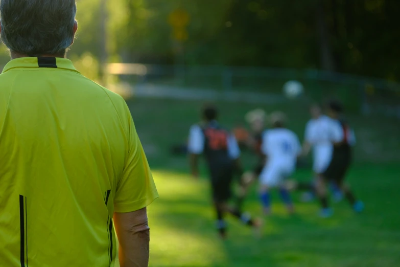 an older man watches his team play a game of soccer