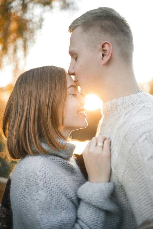 a man and a woman hugging each other and kissing with the sun glaring down