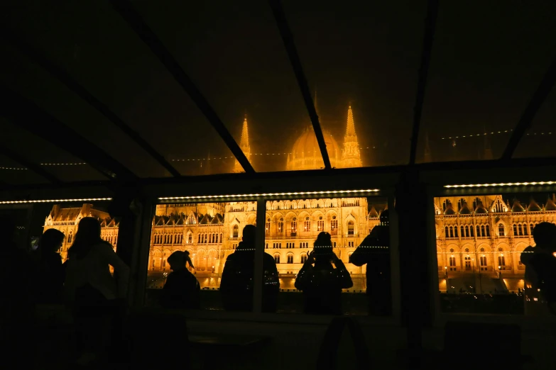 the silhouettes of people are near buildings lit up at night