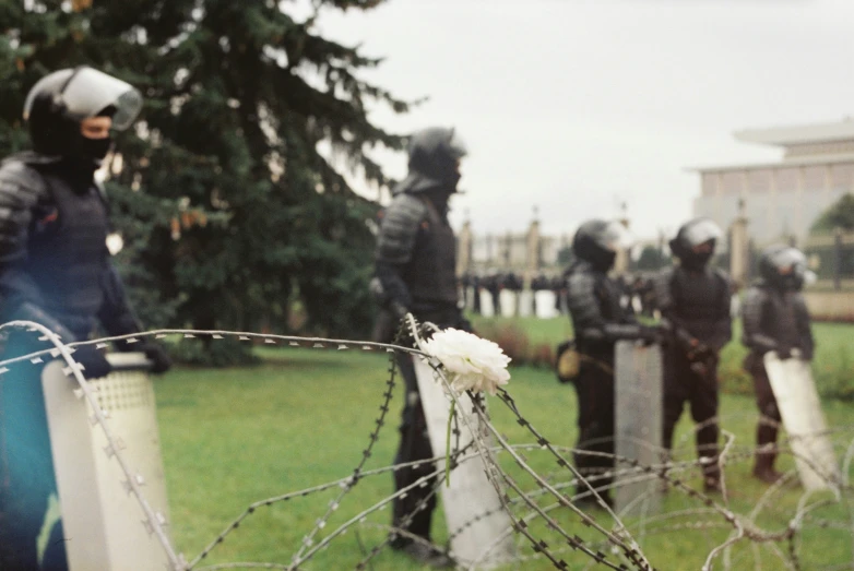 a group of people standing around a barbed wire fence