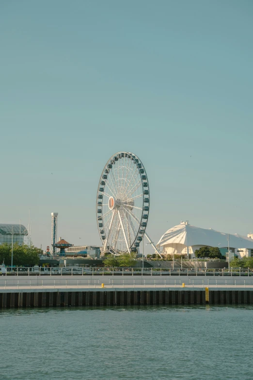 a ferris wheel stands above the water in front of a building